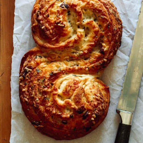 Cheesy roasted garlic and herb pane bianco with a knife.