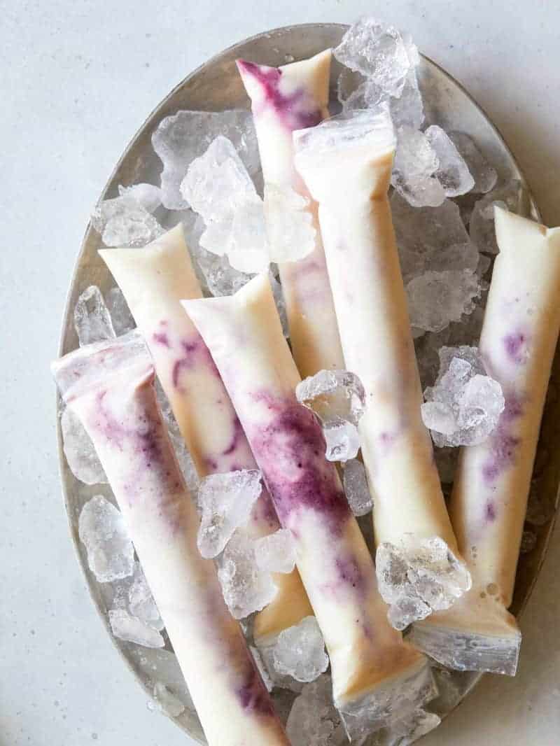 Blackberry Pineapple and Coconut Swirl Pops on a platter with ice. 