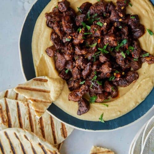 Spiced lamb over roasted garlic hummus with pita on the side.