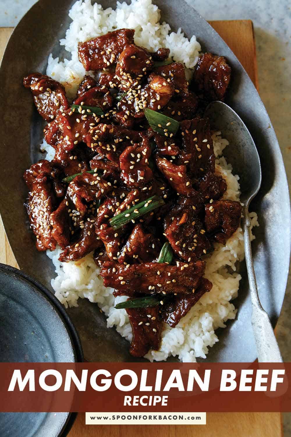 Mongolian Beef on a platter over rice with a spoon in it.
