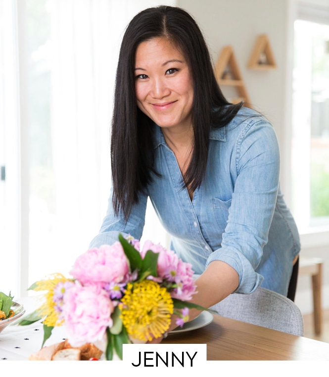 A beautiful smiling woman leaning over a table with flowers.