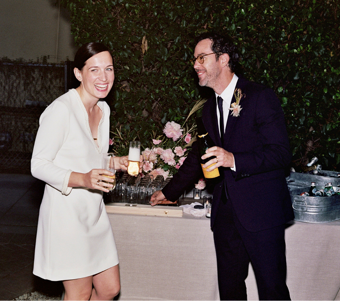 An ecstatic newly married couple with a champagne bottle and glasses.