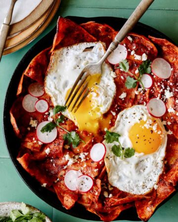 A recipe for easy Chilaquiles with a fork that has broken an egg yolk.