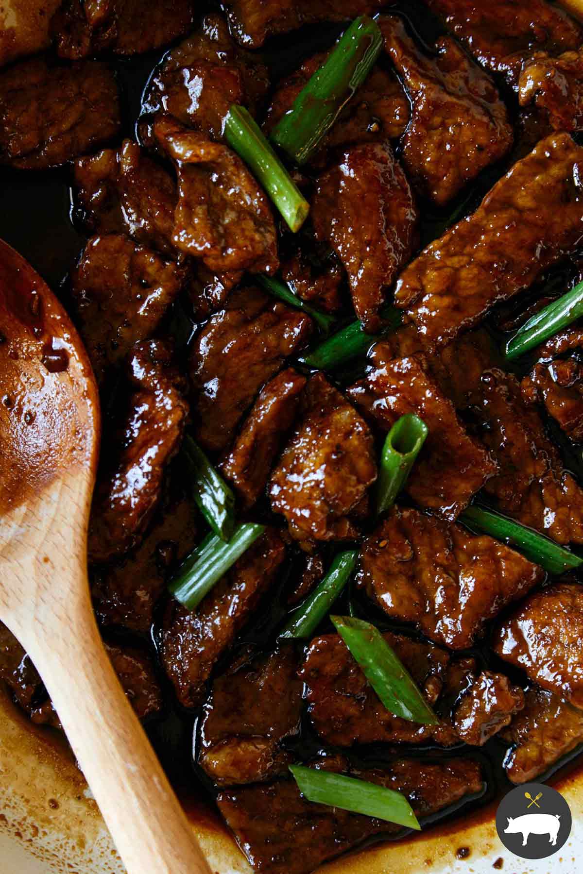 Mongolian beef in a skillet with green onions.