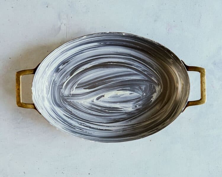 A buttered oval baking dish on a surface.