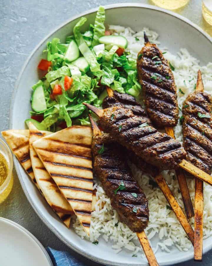 Lamb kofta on rice with pita triangles and salad.