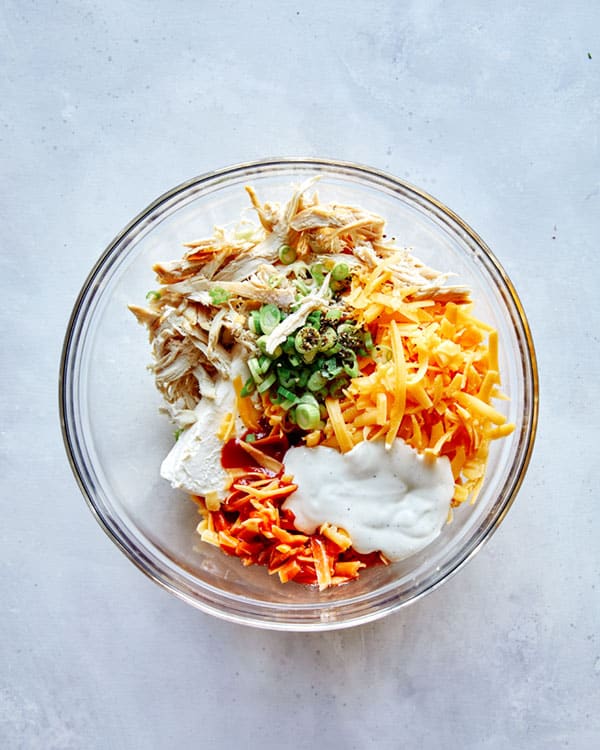 Buffalo chicken dip ingredients in a glass bowl.