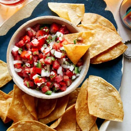 Pico de gallo in a bowl with chips on the side.