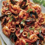 Frutti Di Mare recipe on a platter with basil leaves on the side.