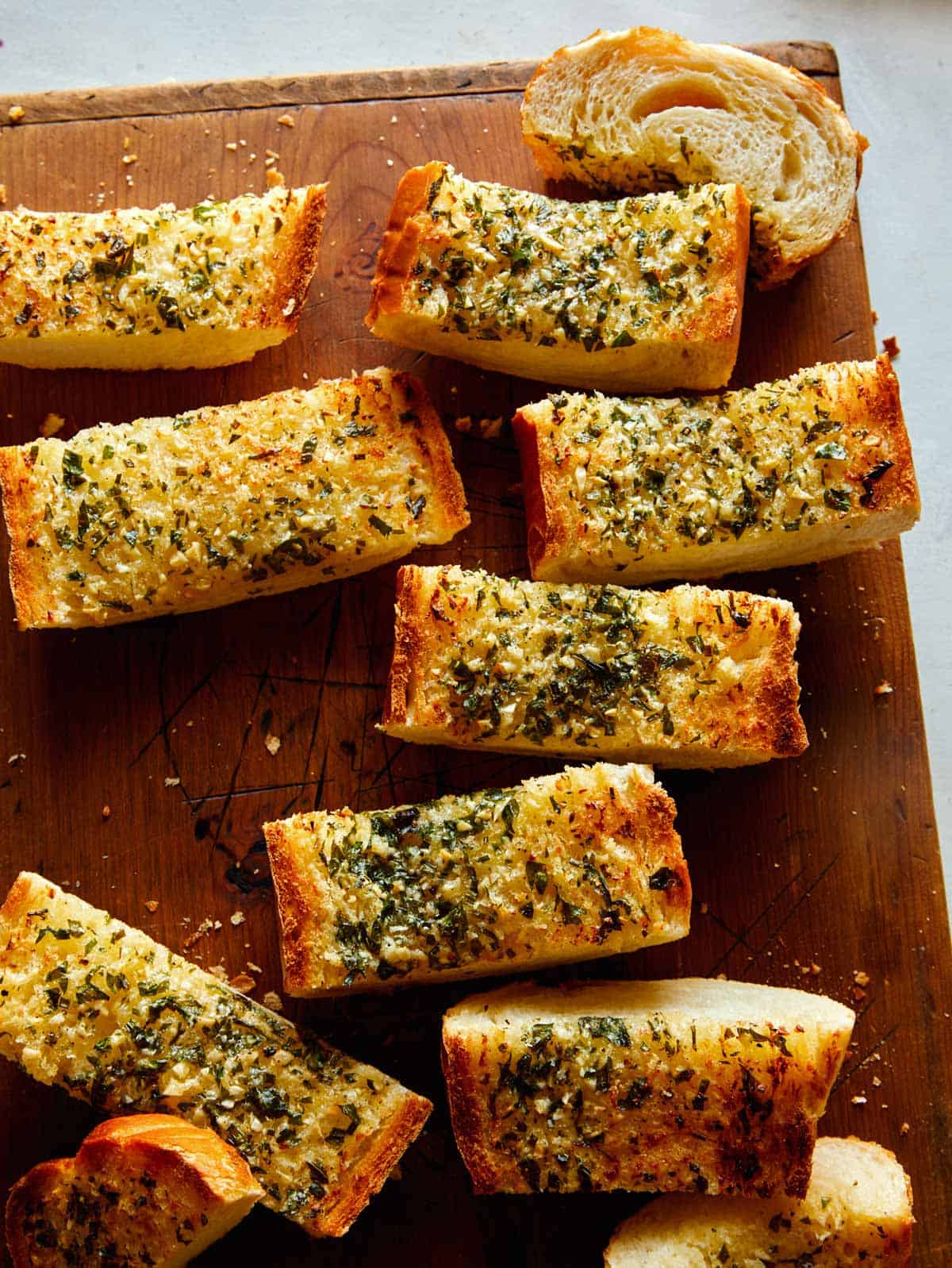 Garlic bread sliced on a cutting board. 