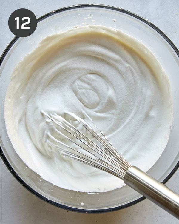 Whipped cream with stiff peaks in a bowl.