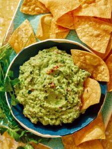 Guacamole recipe in a bowl with chips on the side.