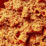 Close up in a skillet of romesco sauce with breadcrumbs on top.