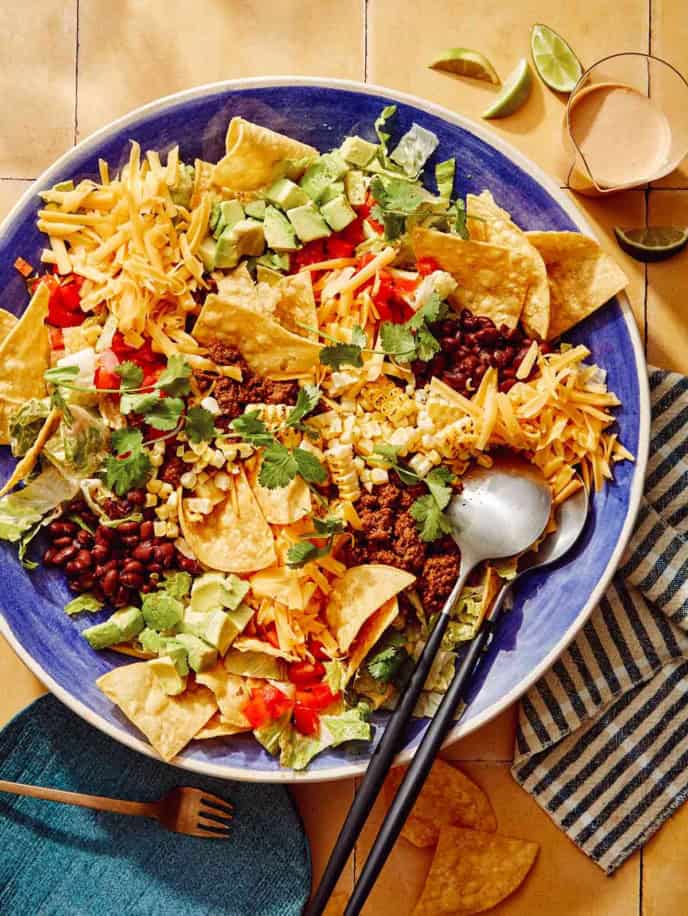 Taco salad in a big bowl with a plate on the side.