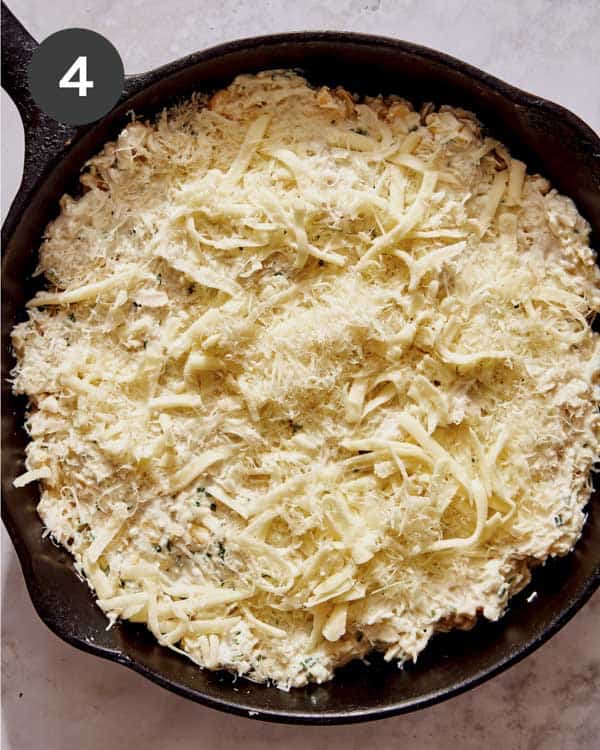 Crab dip mixture in a skillet with cheese sprinkled on the top.