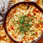 Crab dip in a skillet on a table with chips on the side.