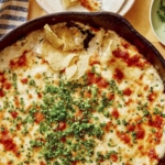 Crab dip recipe in a skillet with potato chips on the side.