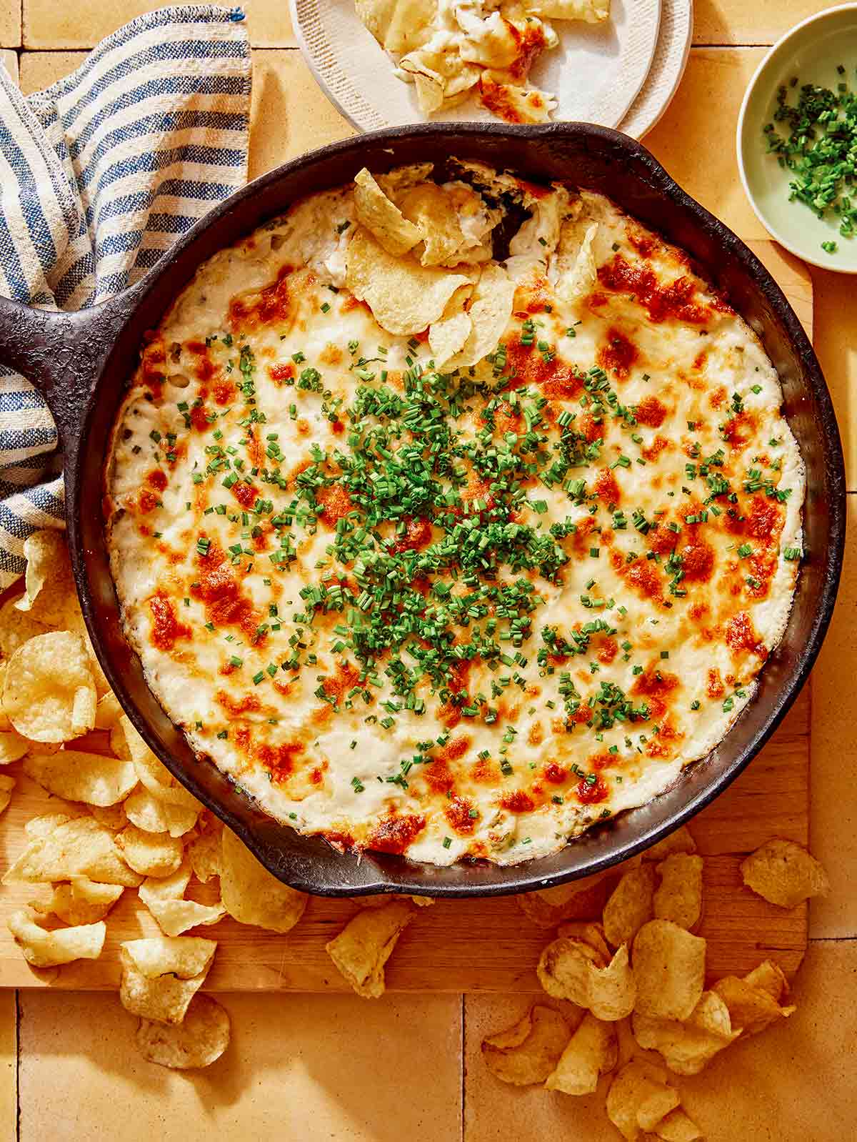 Crab dip in a skillet on a table with chips on the side.