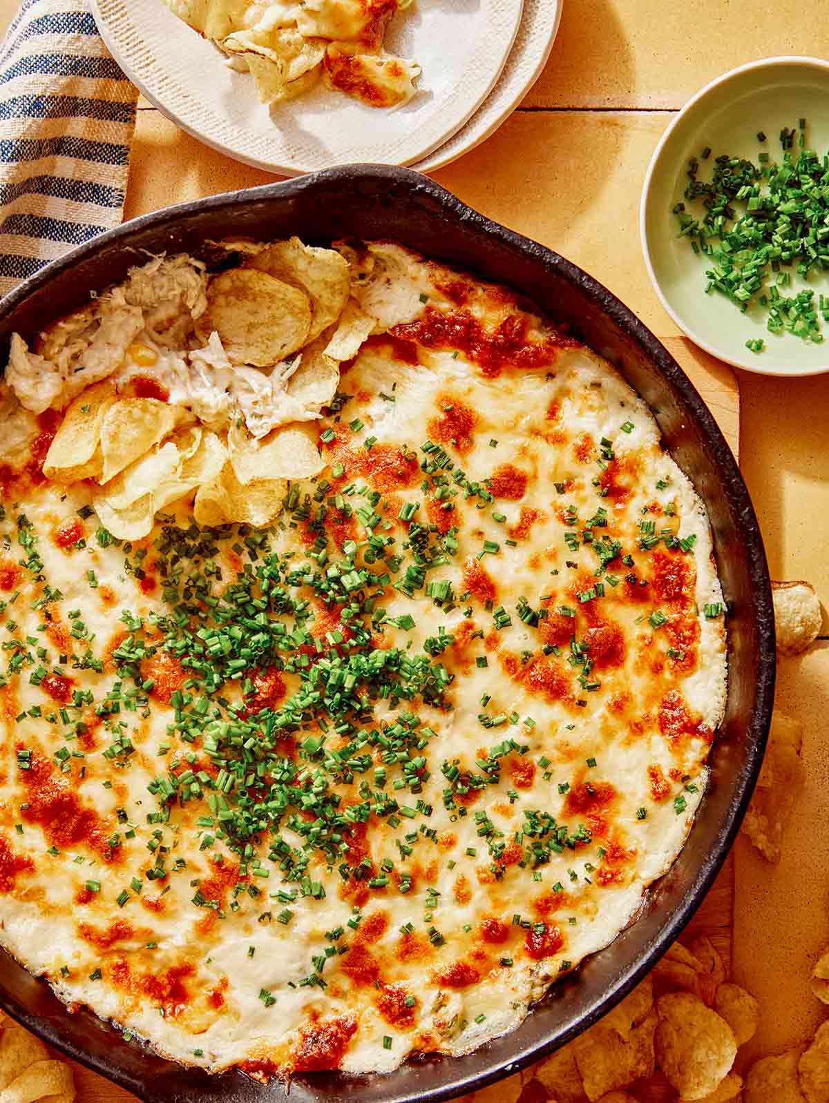 Crab dip recipe in a skillet with potato chips on the side.