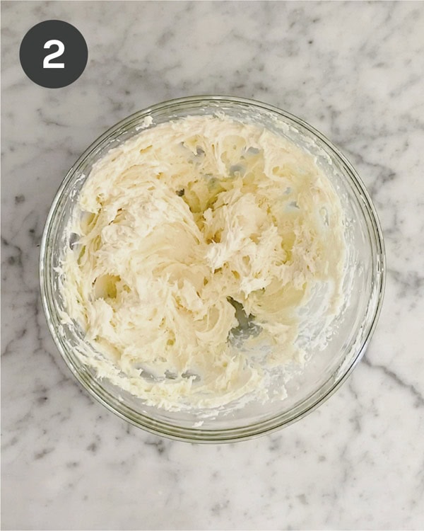 Whipped cream cheese and honey together in a glass bowl. 