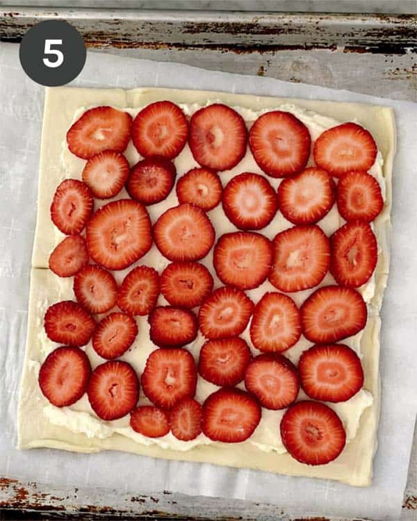 A puff pastry sheet layered with sliced strawberries. 