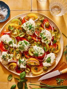 Tomato salad on a plate with herbs on the side.