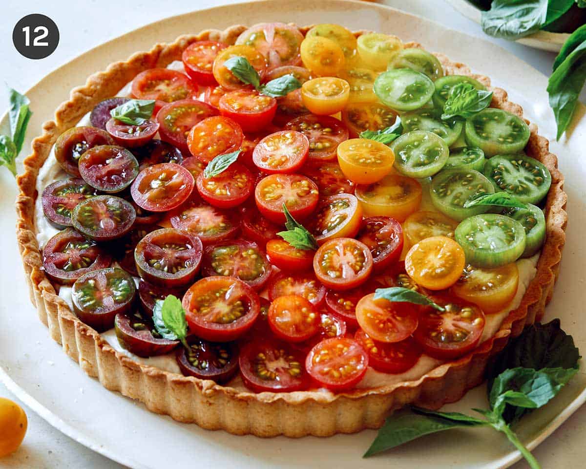 Tomato tart on a platter with white wine in the background.
