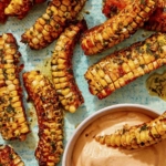 Air fryer corn ribs recipe on a platter with a dipping sauce.