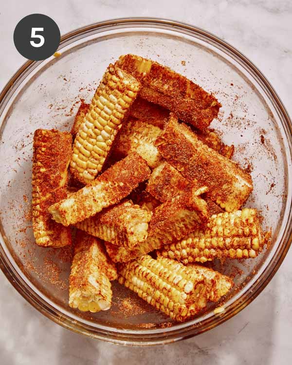 Corn ribs in a bowl with seasoning all over them.