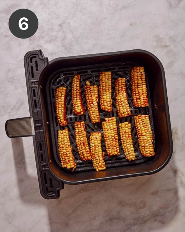 Seasoned corn ribs in an air fryer basket.