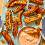 A platter of corn ribs with sauce, and a corn rib dipping in sauce.