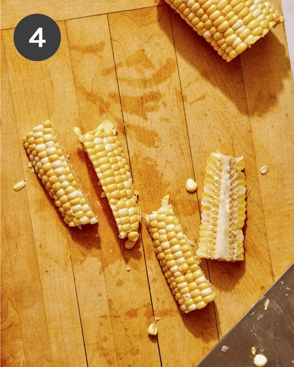 A corn on the cob being cut into fourths.