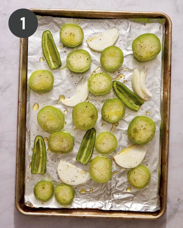 Tomatillo salsa ingredients on a baking sheet ready to be put in the oven. 