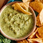 Tomatillo salsa in a bowl with chips on the side.