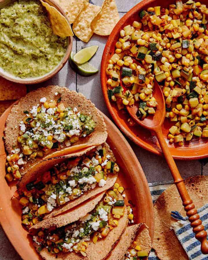 Vegetarian tacos on a platter with the zucchini and corn filling on the side.