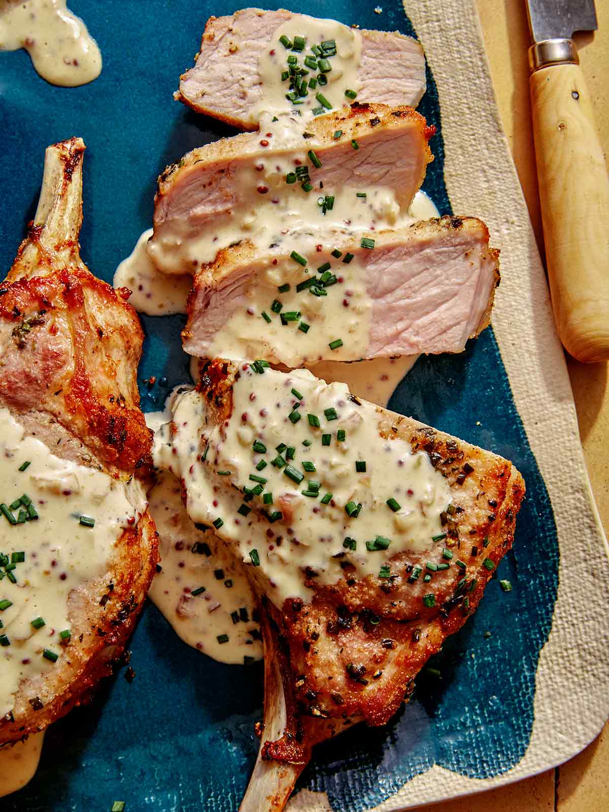 Air fryer pork chops on a platter up close with a sauce over top.