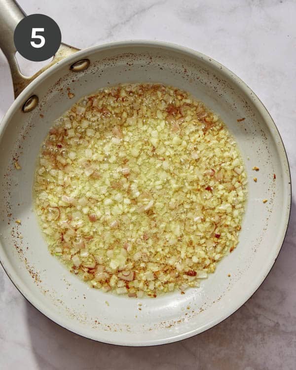 Garlic and shallots cooking in a skillet to make a cream sauce. 