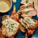 Air fryer pork chops on a platter up close with a sauce over top.