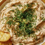 Smoked salmon dip served in a bowl with crackers on the side.